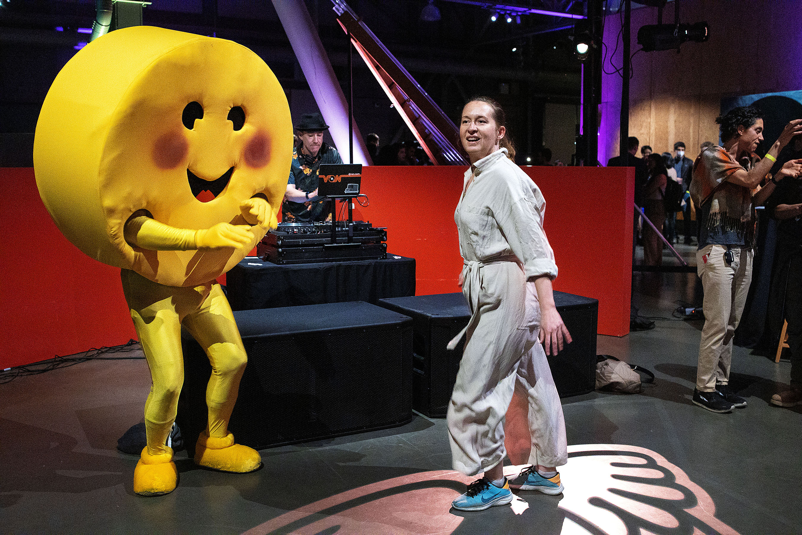 An individual dressed as the hugging face emoji dances with attendees of the event “Open Source AI Meetup with Hugging Face CEO” during the event at the Exploratorium in San Francisco, California on March 31, 2023. Almost 4,300 people RSVPed on Partiful with event organizers referring to it as “AI Woodstock” due to the massive interest in attending. Hugging Face is a company that develops tools for building applications using machine learning. AI builders were spread throughout the event giving demos of what they are working on.  